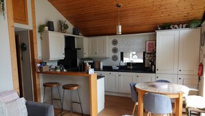 A modern kitchen with white cabinets, wooden countertops, and a central island with stools. - Boutique, 3 bedroom lodge in the heart of Northumberland with private hot tub (Newcastle upon Tyne)