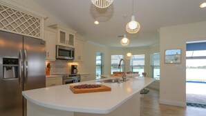 A modern kitchen with a central island, stainless steel appliances, and pendant lighting. - Blue Marlin | Lake front | Pool | Panorama Screen (Port Charlotte)