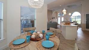 A dining area with a round table set for four, featuring woven placemats and blue plates. - Blue Marlin | Lake front | Pool | Panorama Screen (Port Charlotte)