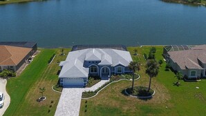 A large house with a spacious driveway, a garage, and a well-maintained lawn. - Blue Marlin | Lake front | Pool | Panorama Screen (Port Charlotte)