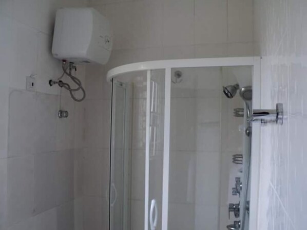 A modern bathroom with a glass-enclosed shower, a white toilet, and a wall-mounted water heater.