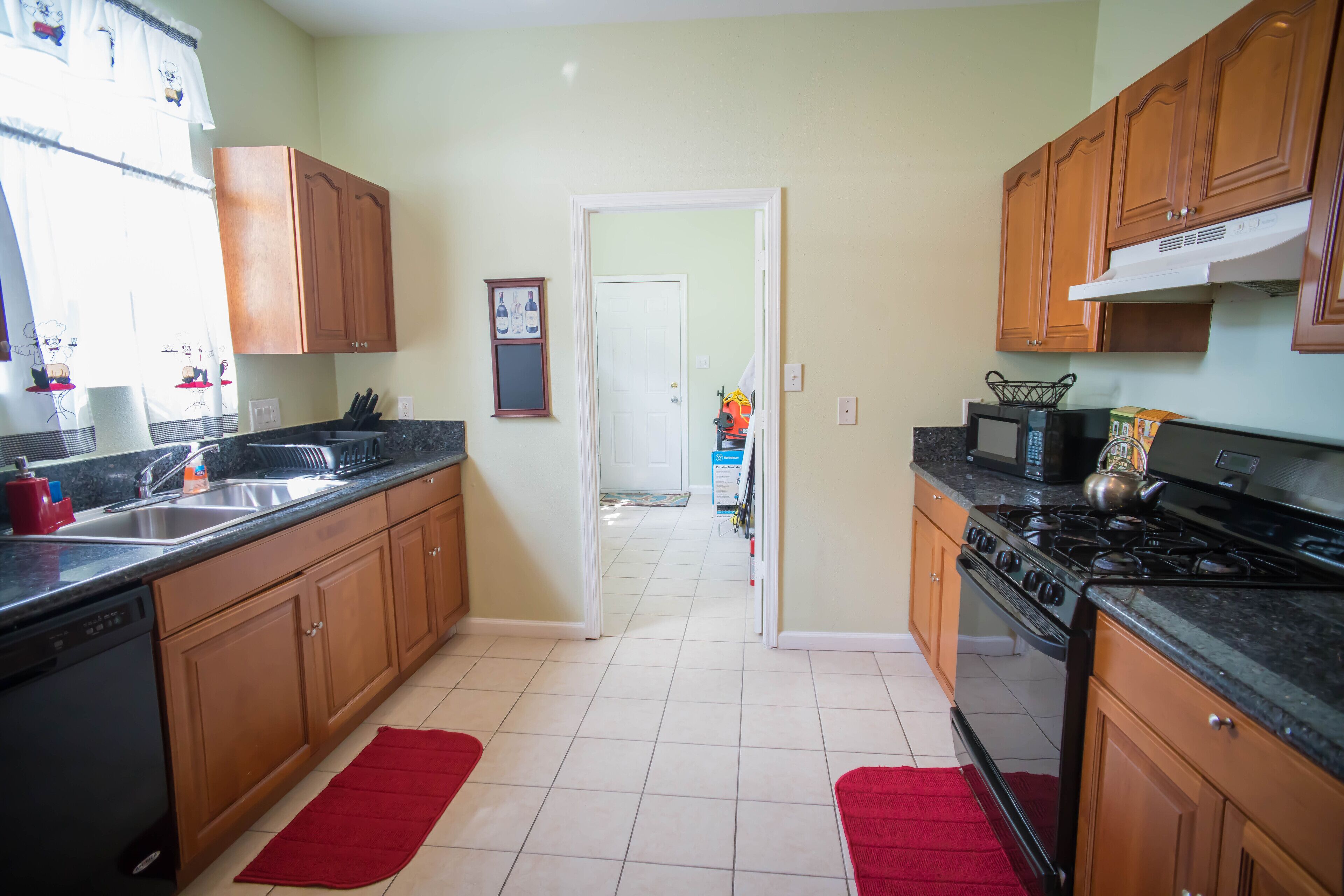 Una cocina con armarios de madera, estufa, microondas y lavabo.
