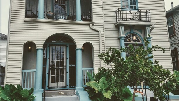 Een huis met twee verdiepingen, een voortuin, een balkon en een grote voordeur.
