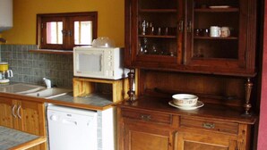 A kitchen with wooden cabinets, a microwave, a sink, and a dishwasher. - Mökki "the Ann the Annonciade" (LE LUC)
