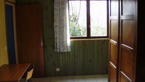 A room with a wooden floor, a window with a curtain, a wooden door, and a table with a chair. - Mökki "the Ann the Annonciade" (LE LUC)
