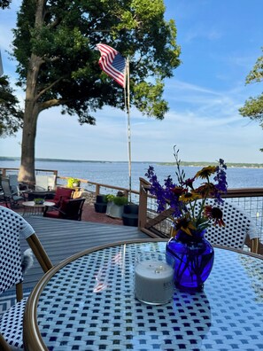 A deck with outdoor seating, a flag, and a vase with flowers.