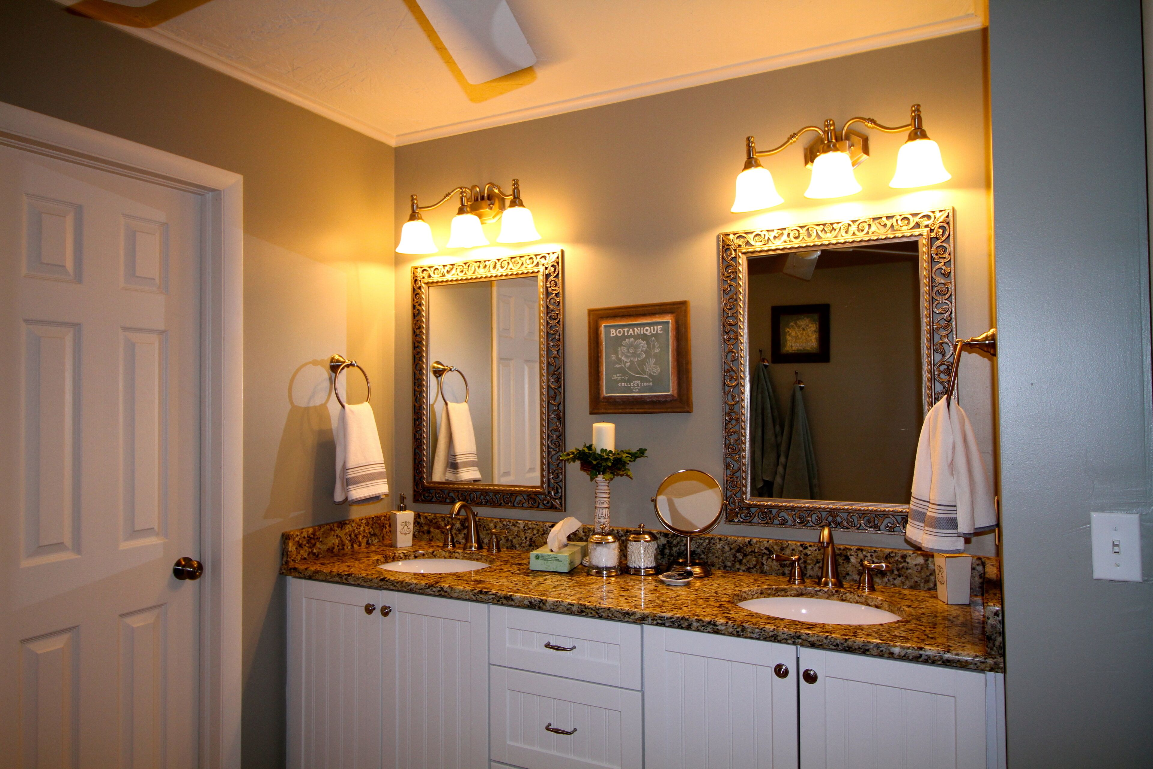 A bathroom with two sinks, a vanity, and a large mirror with ornate frames.