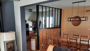 Een moderne woonkamer met een bank, een glazen tafel met een kaars, en een keuken op de achtergrond.
