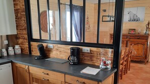Een keuken met houten kastjes, een zwart aanrecht, een koffiezetapparaat en een prullenbak.