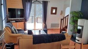 Een woonkamer met een bank, televisie en een eethoek met een tafel en stoelen.