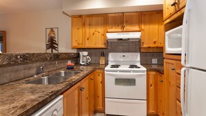 A kitchen with wooden cabinets, a white stove, a microwave, and a granite countertop. - Very Attractive Spacious Condo.  Excellent Location.  Must See! (Whistler)