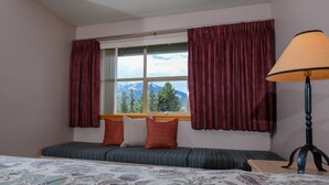 A room with a bed, a bench with pillows, a window with curtains, and a lamp. - Very Attractive Spacious Condo.  Excellent Location.  Must See! (Whistler)