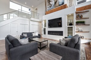 A spacious living room with a large TV, grey sofas, and a wooden coffee table. - Waterfront Lake Erie near Niagara Wine Region (Dunnville)