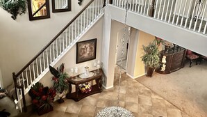 Un vaste espace de vie doté d’un haut plafond, une table à manger décorée de bougies et un escalier menant à un niveau supérieur.
