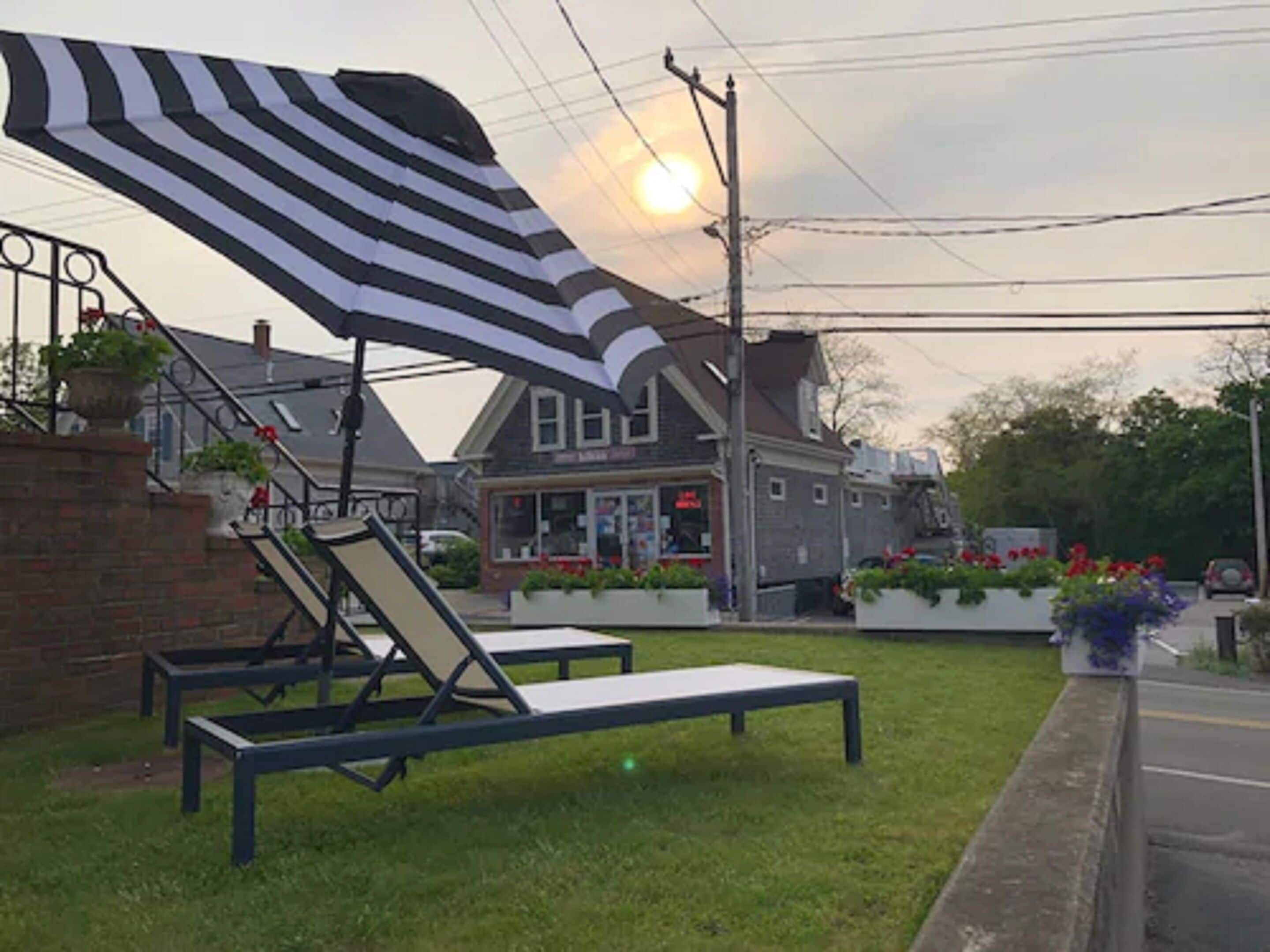 Un espacio cubierto de césped con dos sillones y un toldo a rayas.