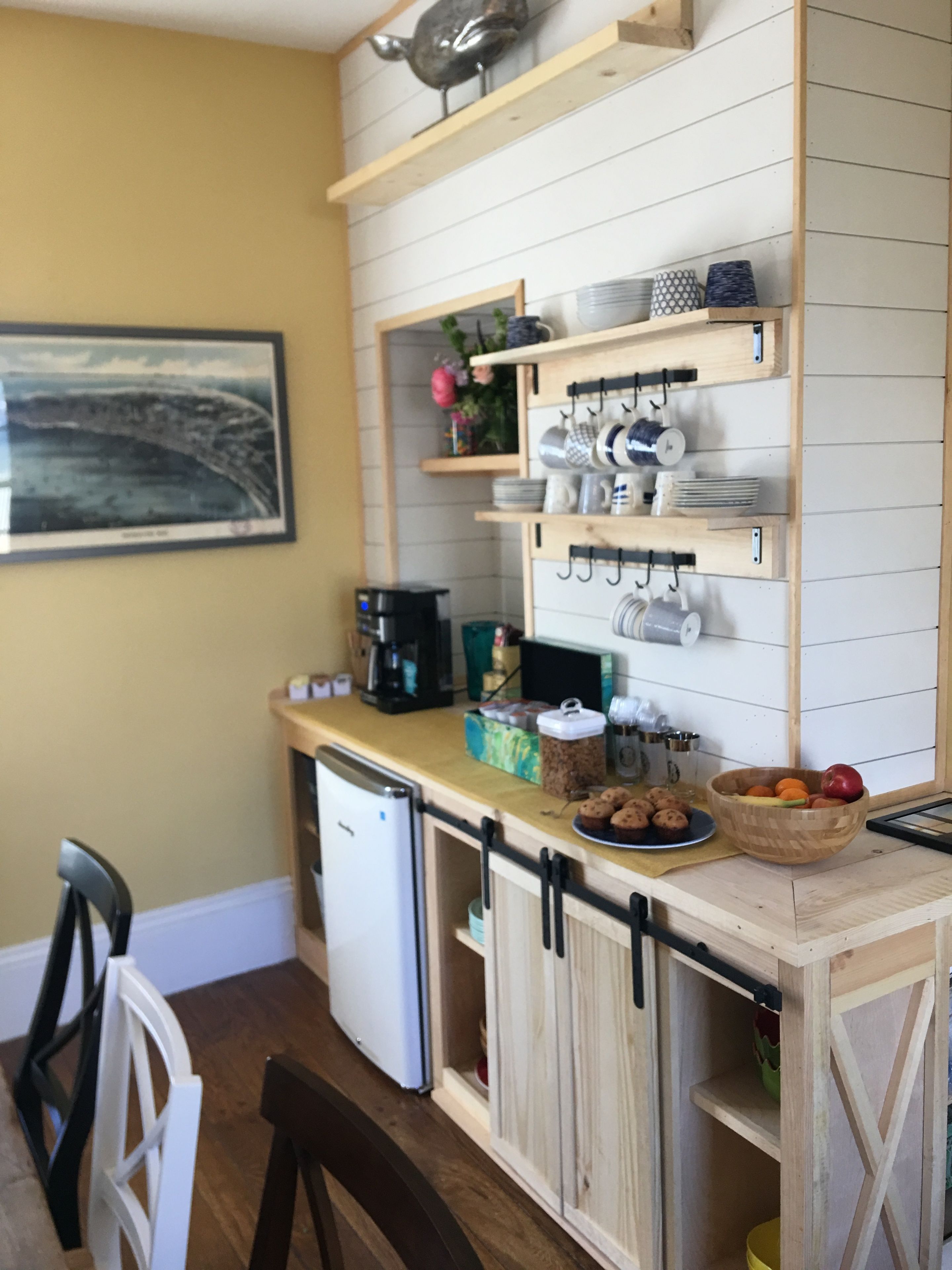 A compact kitchen with wooden cabinets, a coffee maker, and a fruit bowl.