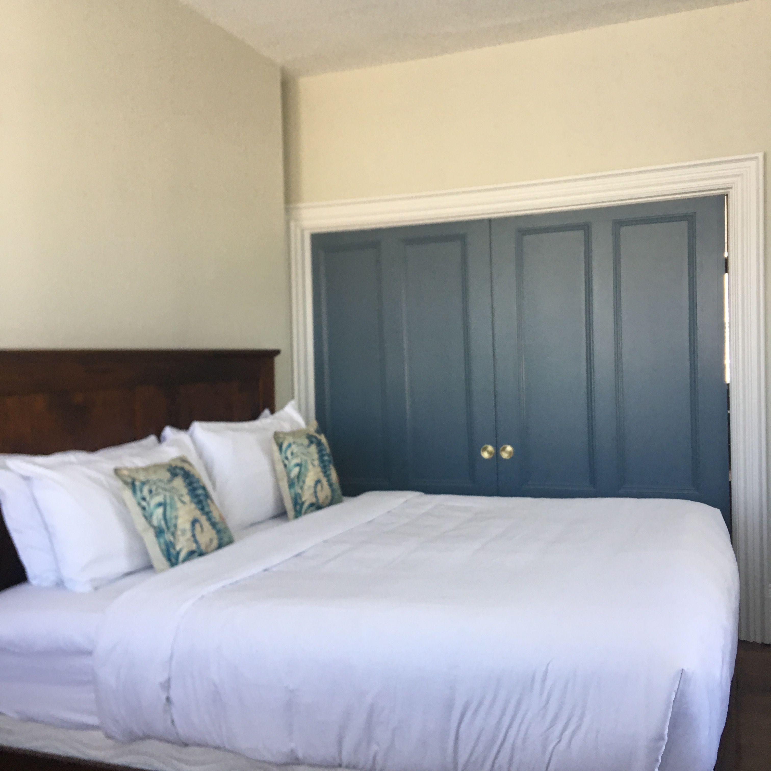 Un dormitorio con cama, almohadas y una puerta azul.