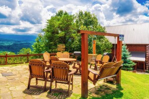 An outdoor patio with wooden chairs and tables, a swing, and a view of the mountains. - Majestic Mtn Lodge: Mtn Views, Theater, Games, Resort Pool, Hot Tub, Wifi (Sevierville)
