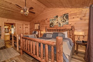A log cabin bedroom with a wooden bed, a ceiling fan, and a painting on the wall. - Majestic Mtn Lodge: Mtn Views, Theater, Games, Resort Pool, Hot Tub, Wifi (Sevierville)