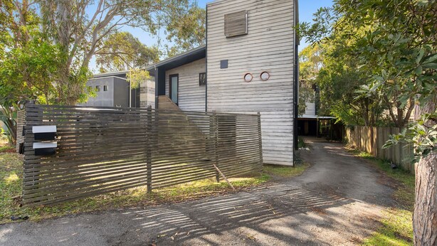 Une maison moderne avec une clôture en bois, une allée et un jardin.