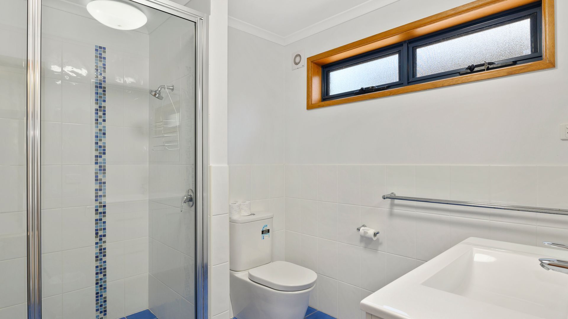 A bathroom with a glass shower enclosure, a toilet, and a sink.