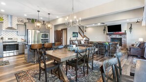 Une cuisine spacieuse dotée d’appareils électroménagers modernes, un coin repas avec des meubles en bois et un salon confortable agrémenté d’une cheminée.