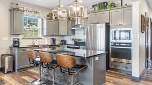 Une cuisine moderne avec des meubles gris, des appareils en acier inoxydable et un îlot central doté de tabourets de bar.