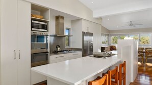 Una cocina moderna con electrodomésticos integrados, una isla grande y un comedor con sillas de madera.