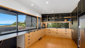 Eine moderne Küche mit Holzausstattung, einem Edelstahlspülbecken und Meerblick.