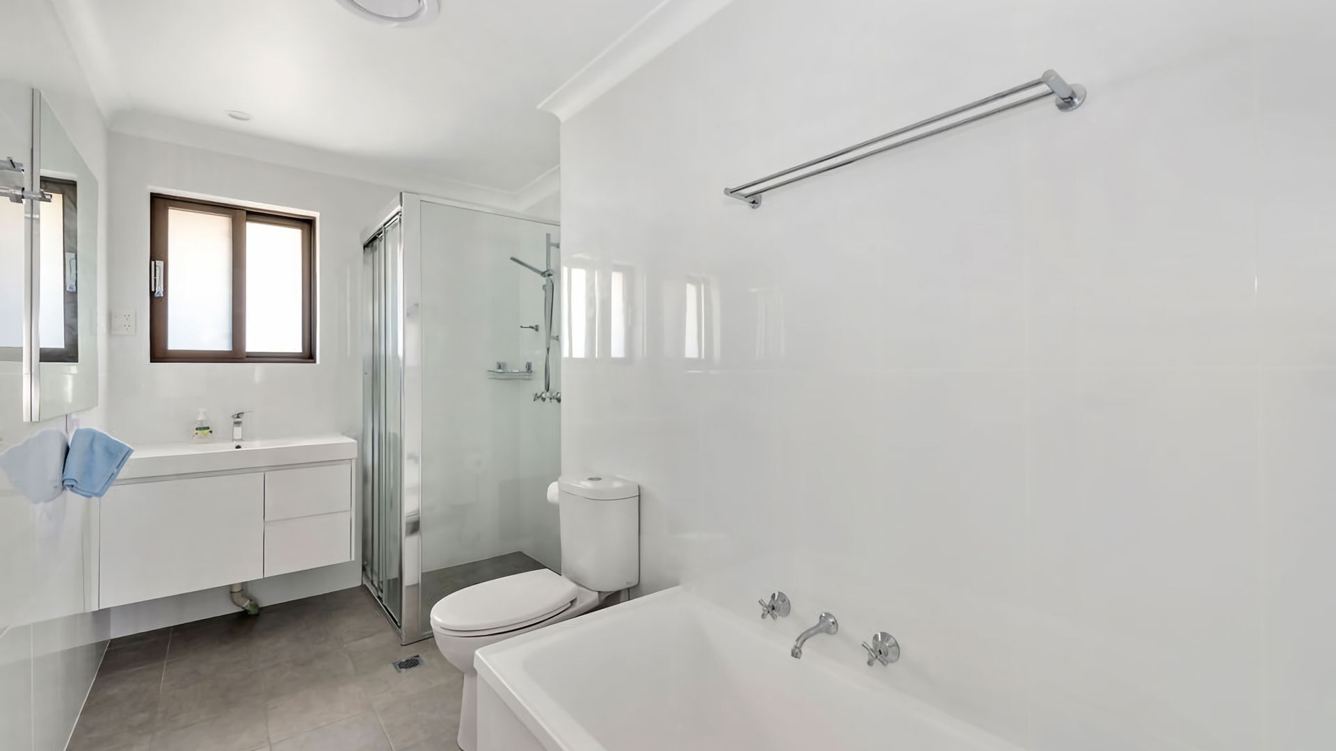 A modern bathroom with a glass shower enclosure, a white toilet, and a bathtub.