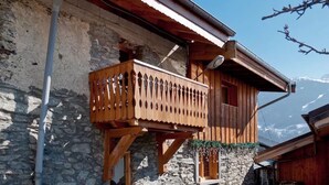 A wooden chalet with a balcony, stone walls, and a mountain view. - Mountain village apartment overlooking 3 Valleys (Montagny)