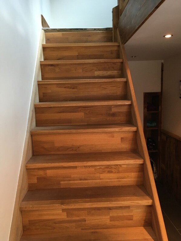 Un escalier en bois avec une main courante sur le côté droit.