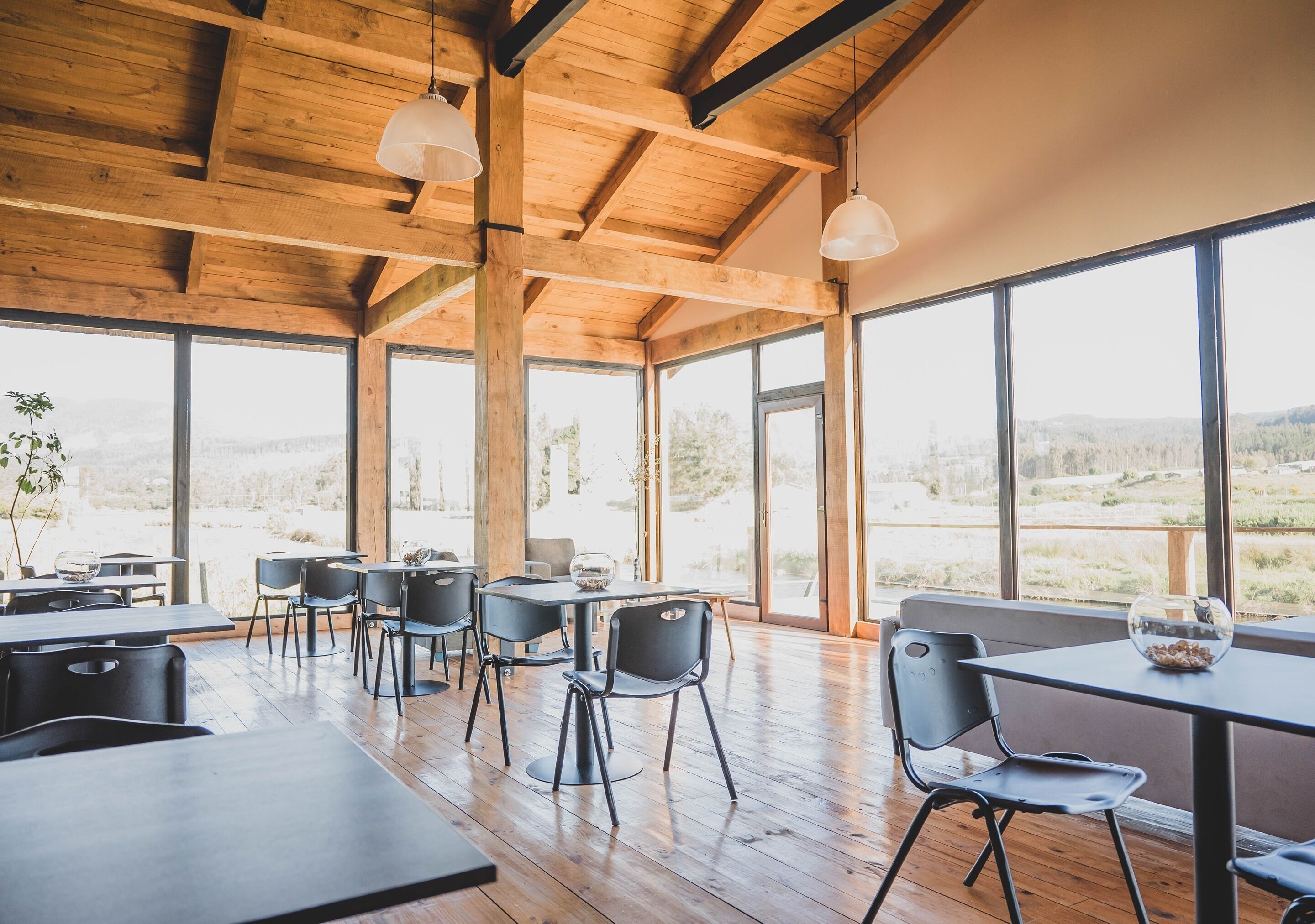 A spacious dining area with wooden beams, large windows, and modern furniture.