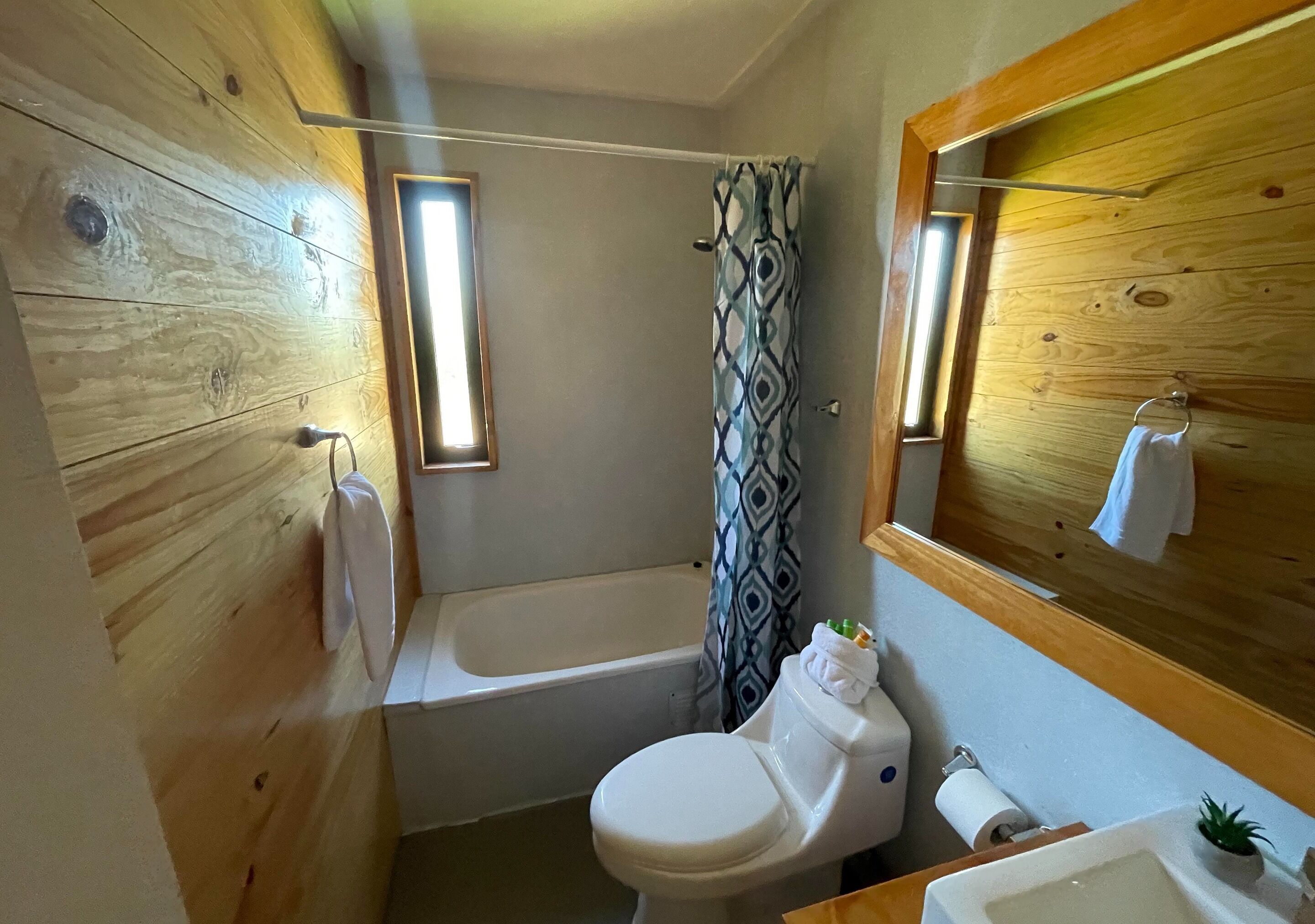 Un baño pequeño con inodoro blanco, bañera y cortina de ducha.