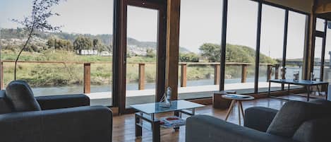 A spacious room with large windows, wooden flooring, and modern furniture including sofas and a coffee table.