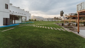 A modern building with a flat roof, large windows, and a well-maintained lawn with pathways. - Captain's Cove (Concon)