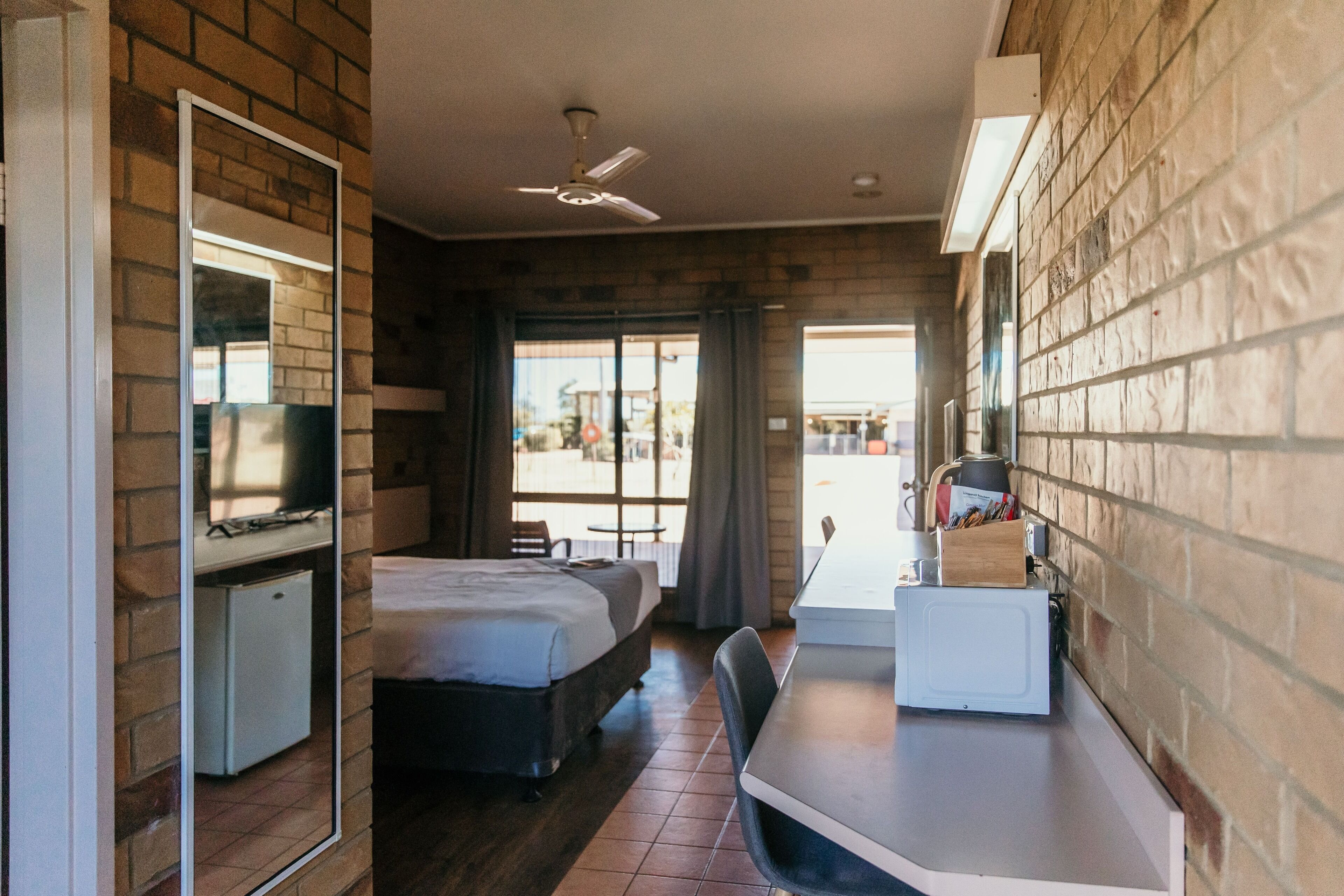 A hotel room with a bed, a desk, a television, and a small refrigerator.