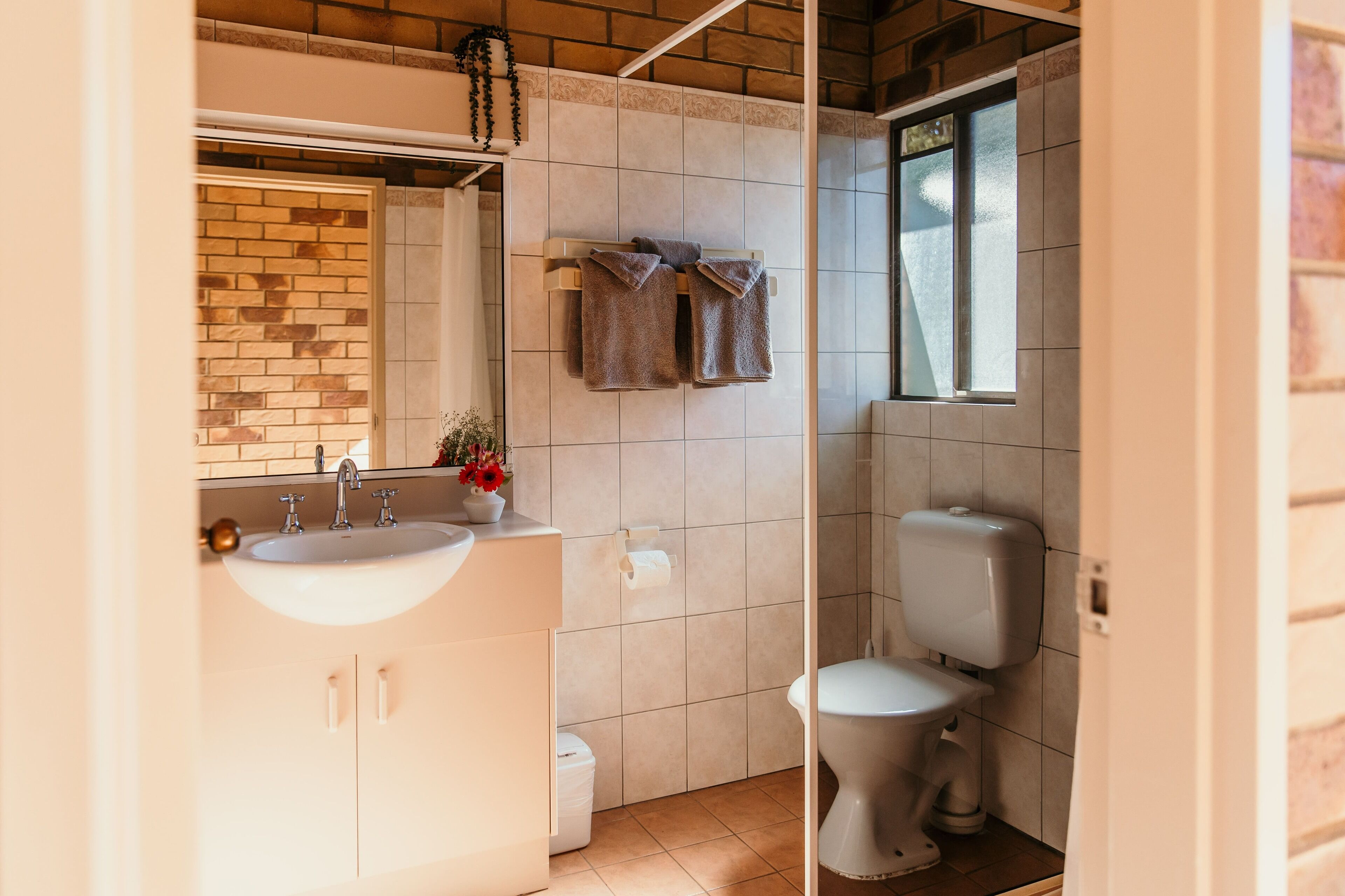 Un bagno con lavandino, specchio, portasciuga, WC e una finestra.