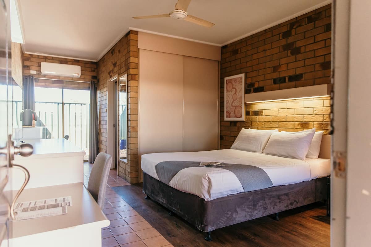 A bedroom with a bed, a desk, and a chair.