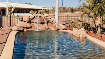 Una piscina al aire libre, sillones reclinables de piscina