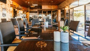 Un restaurante con interior de madera, mesas de vidrio y sillas de mimbre.