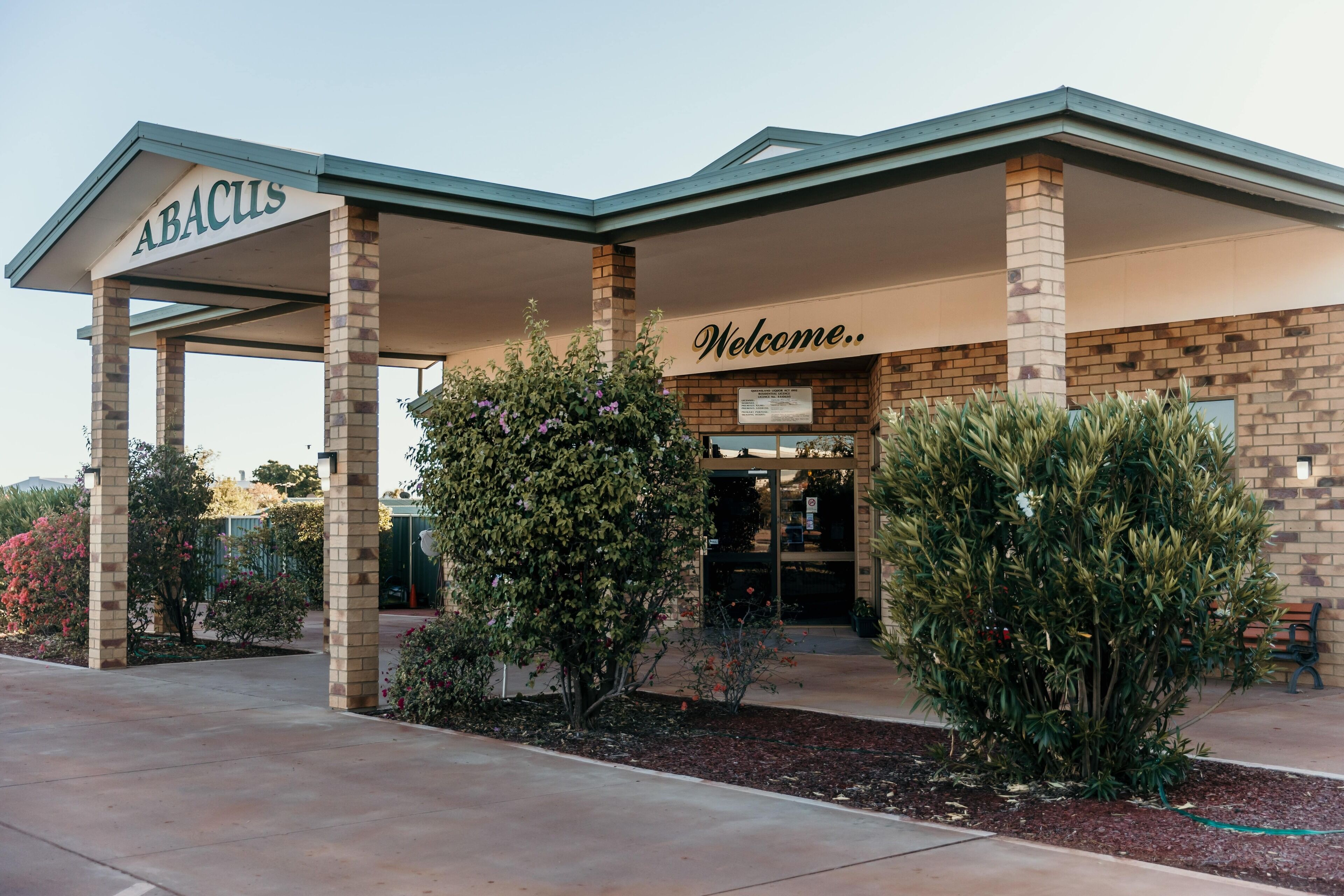 A hotel entrance with a covered area labeled "ABACUS" and a "Welcome" sign.