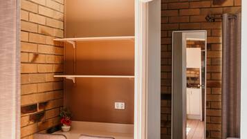 Una habitación con pared de ladrillo, suelo de madera, una mesa con sillas y un espejo en la pared.