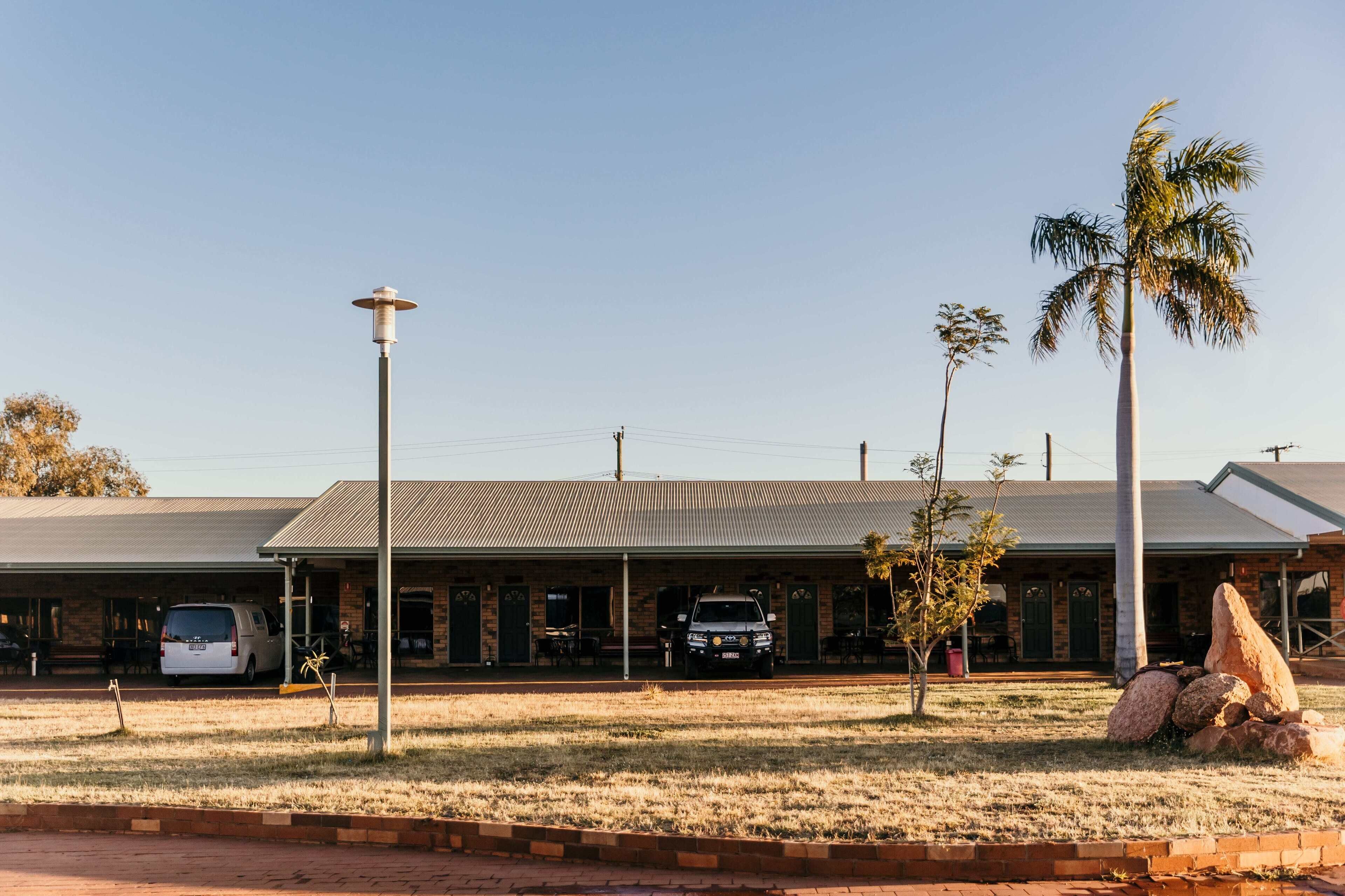 A building with a flat roof, a paved parking area, and a grassy lawn.
