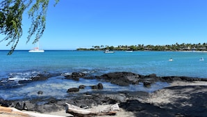A beach with clear blue water, rocky shoreline, and boats in the distance. - Great Getaway at Shores at Waikoloa! (Waikoloa)