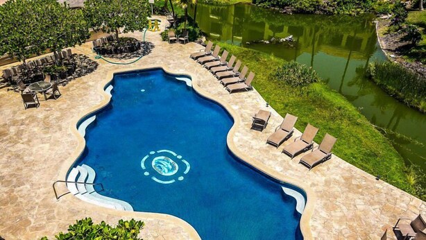 A swimming pool with a unique shape, surrounded by lounge chairs and a small garden area. - Great Getaway at Shores at Waikoloa! (Waikoloa)