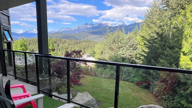A balcony with a view of mountains, a red chair, and a wooden table with magazines. - SUPER SUMMER GETAWAY  Views + POOL + HOT TUB (WD, FP) (Whistler)