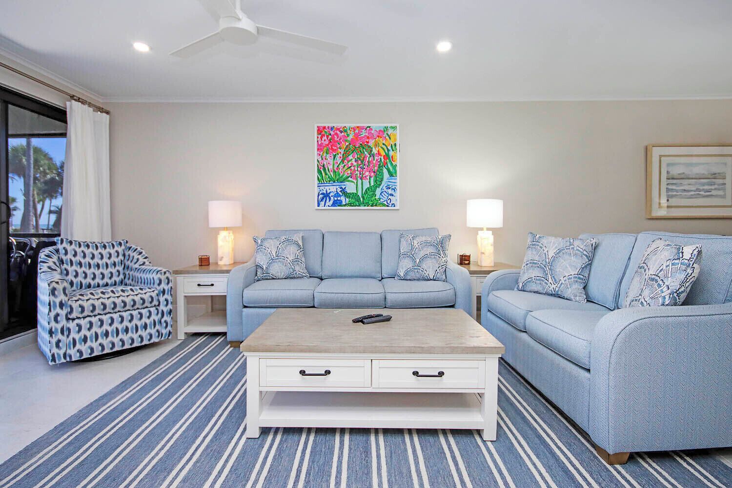 A living room with a sofa, a patterned armchair, a coffee table, and two lamps.