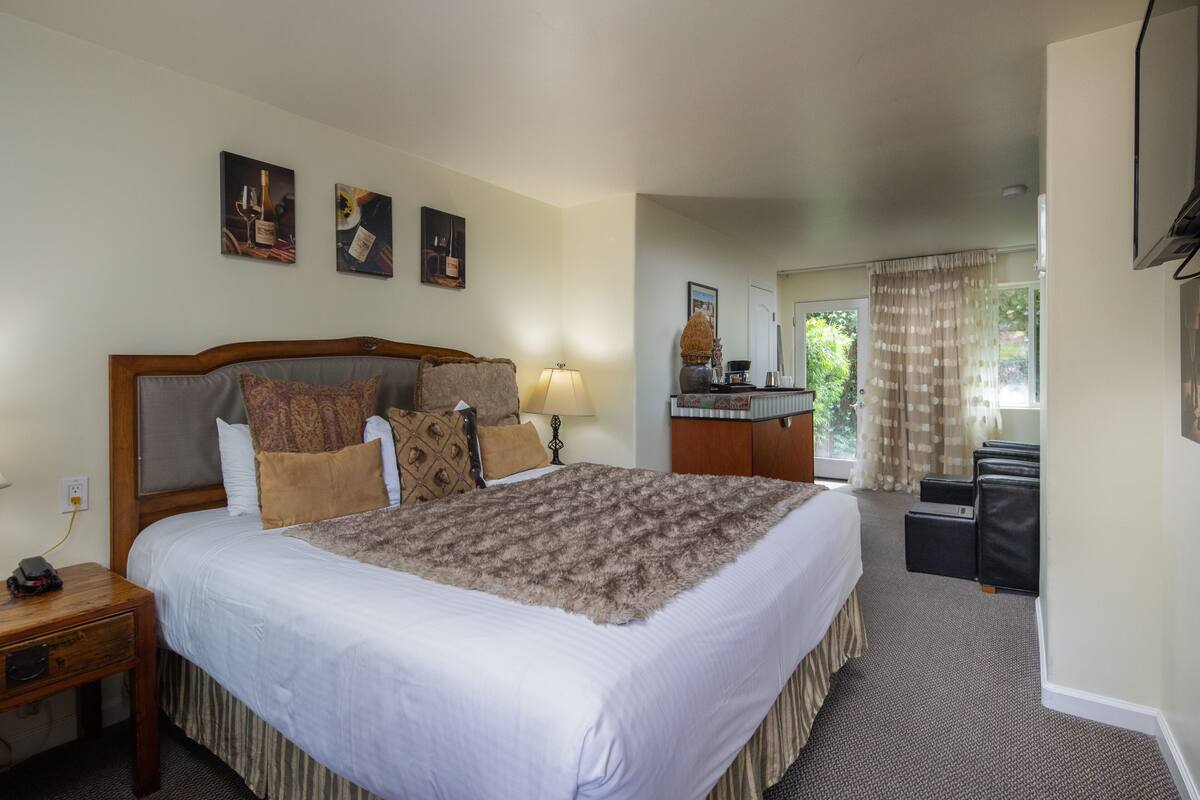 A hotel room with a large bed, a desk, a chair, and a television.