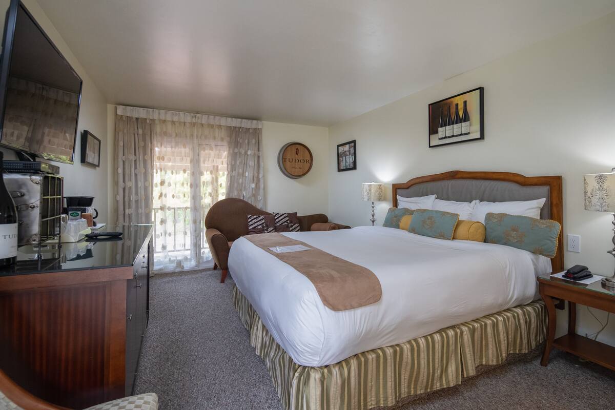 A hotel room with a large bed, a desk with a computer, a chair, and a TV.